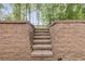 Exterior stone staircase ascending through a walled entrance to a landscaped backyard at 2055 Timberland Dr, Cumming, GA 30040