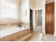 Bright bathroom features a soaking tub with a window, tile surround, and a glass door shower at 3512 Centerville Rosebud Rd, Snellville, GA 30039