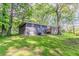 Backyard view of the house shows the brick exterior, a small deck and a lush, green, partially shaded yard at 545 Fayetteville Rd, Fairburn, GA 30213