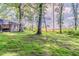 The grass backyard with some trees growing along a field beside this blue house has a small wooden deck at 545 Fayetteville Rd, Fairburn, GA 30213