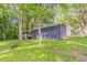 A blue house with a small wood deck is on a grassy lot with large trees in the front and sides at 545 Fayetteville Rd, Fairburn, GA 30213