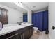 Bathroom featuring a dark wood vanity with a white marble top and shower with blue curtain at 5068 Bentwater Sw Ln, Lilburn, GA 30047
