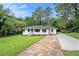 Wide shot of a single-story home featuring a well-manicured lawn, a long driveway, and mature trees at 2406 Tilson Rd, Decatur, GA 30032