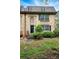 Close-up of a brick townhouse with a black door and manicured bushes at 6980 Roswell Road # A8, Atlanta, GA 30328