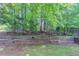 Backyard featuring a tiered retaining wall with greenery, grass and trees at 12241 Cypress Way, Fayetteville, GA 30215