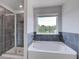 Modern bathroom featuring a glass enclosed shower, soaking tub, and large window at 17 Camellia Dr, Fairburn, GA 30213