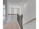 Upstairs hallway features black metal railing, wood handrail, neutral colored carpet, and natural light at 17 Camellia Dr, Fairburn, GA 30213