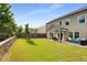 Spacious backyard featuring a well-manicured lawn, retaining wall, and a covered patio area at 122 Grove View Rd, Woodstock, GA 30189