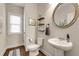 Stylish powder room with a modern pedestal sink, round mirror, and decorative shelving, maximizing space and style at 122 Grove View Rd, Woodstock, GA 30189