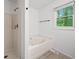 Bathroom featuring a white tub with a shower head and an exterior view out the window at 3310 Southlake Ln, Cumming, GA 30041