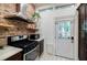 Charming kitchen features exposed brick, stainless steel appliances, and white door leading outside at 549 Atwood Sw St, Atlanta, GA 30310