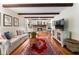 Comfortable living room featuring exposed beams, a brick fireplace, hardwood floors, and neutral decor at 2719 Cravey Ne Dr, Atlanta, GA 30345