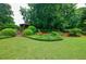 Landscaped backyard with lush grass, a stone wall, and a charming gazebo in the distance at 5318 Brooke Farm Dr, Dunwoody, GA 30338