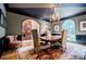 Formal dining room with hardwood floors, classic chandelier, and arched windows overlooking the landscaped yard at 5318 Brooke Farm Dr, Dunwoody, GA 30338