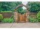 Charming stone and wood garden gate surrounded by lush landscaping at 5318 Brooke Farm Dr, Dunwoody, GA 30338