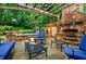 Outdoor fireplace with a stone surround and wooden pergola, nestled among lush landscaping and comfortable seating at 5318 Brooke Farm Dr, Dunwoody, GA 30338