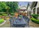 Outdoor patio featuring an ornate dining table, fireplace, jacuzzi, and lush landscaping at 5318 Brooke Farm Dr, Dunwoody, GA 30338