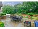 Expansive stone patio featuring an outdoor kitchen, dining area, lush landscaping, and comfortable seating at 5318 Brooke Farm Dr, Dunwoody, GA 30338