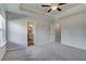 Bright bedroom with soft carpet, neutral walls, tray ceiling, and a modern ceiling fan, two open doorways at 907 Eagle Ave, Riverdale, GA 30296