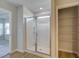 Walk-in shower featuring glass doors, tile surround, and a built-in shower caddy, next to walk-in closet at 907 Eagle Ave, Riverdale, GA 30296
