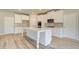 Bright kitchen features an island, white cabinets, stainless steel appliances, and hardwood floors at 162 Haverling Pass, Hampton, GA 30252