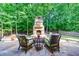 Outdoor patio featuring a stone fireplace and comfortable seating, surrounded by lush greenery and trees at 265 Dogwood Walk Ln, Norcross, GA 30071