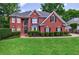 Charming two-story brick home featuring manicured lawn, mature trees, and traditional architectural details at 265 Dogwood Walk Ln, Norcross, GA 30071