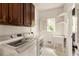 Bright laundry room with wooden cabinets, a washer and dryer, and a utility sink with a window at 320 Kirk Rd, Decatur, GA 30030
