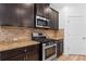 Kitchen features stainless steel range and microwave complemented by warm wood cabinets and granite countertops at 3805 Alden Pl, Cumming, GA 30028