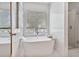 Bright bathroom featuring a soaking tub with a window view and a glass-enclosed shower at 565 Barsham Way, Johns Creek, GA 30097