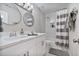 Bathroom with a dual sink vanity, two round mirrors and a tub-shower combination at 565 Barsham Way, Johns Creek, GA 30097
