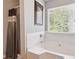 Bright bathroom featuring a tiled tub, shower with curtain, and a large window at 1127 Oak Hollow Ct, Hampton, GA 30228