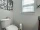 Clean and modern bathroom featuring a toilet, decorative art and a window for natural light at 1127 Oak Hollow Ct, Hampton, GA 30228