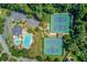 Aerial view of tennis courts and community pool with lounge seating surrounded by mature trees at 1199 Kenway Se Cir, Smyrna, GA 30082