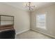 A bedroom with neutral walls and carpet, modern light fixture, and a window with blinds at 1303 Hill Se St, Atlanta, GA 30315