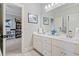Bright bathroom featuring double sinks, white cabinets, and decorative mirrors with an open view to the adjacent room at 1525 Camden Cove Dr, Cumming, GA 30040