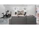 Cozy living room area with a large gray couch, television, mirrors, exercise bike and gray floors at 1525 Camden Cove Dr, Cumming, GA 30040
