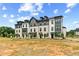 Series of modern townhouses with varied exteriors, surrounded by undeveloped land and blue skies at 525 Rubato Knl, Mcdonough, GA 30253
