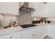 Close up on kitchen details including white cabinets, backsplash, countertop and stovetop with range hood at 525 Rubato Knl, Mcdonough, GA 30253