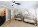 Bright Bedroom with giraffe-themed wallpaper, bronze-colored cribs, and hardwood flooring at 1021 Wetherby Way, Alpharetta, GA 30022