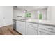 Kitchen island featuring a sink, dishwasher, and white cabinets, complemented by granite countertops at 3181 Meadowstone Sw Ln, Atlanta, GA 30331