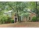 View of the brick and stucco home showcasing mature trees and landscaping in a tranquil, wooded setting at 175 River Run, Roswell, GA 30075