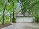 Three-car garage with automatic doors and paved driveway, nestled amongst mature trees at 175 River Run, Roswell, GA 30075