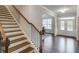 Bright foyer with hardwood floors, staircase with metal spindles and view into adjacent living space at 4240 Summer Breeze Way, Buford, GA 30518