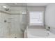Bright Primary bathroom showcasing separate shower and soaking tub with light gray tiled floors and walls at 4240 Summer Breeze Way, Buford, GA 30518