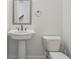 Well-lit powder room with a pedestal sink, a framed mirror, and a white toilet at 600 Luckett Ct, Smyrna, GA 30080
