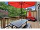 Inviting patio with wood deck, outdoor dining set under a red umbrella, and comfortable seating with plush red cushions at 600 Luckett Ct, Smyrna, GA 30080