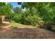 View of lush backyard with trees, vegetation and small deck at 90 Cypress Dr, Covington, GA 30016