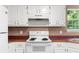 Close-up of kitchen featuring white appliances, cabinetry and hardwood floors at 90 Cypress Dr, Covington, GA 30016