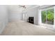 Open-concept living room with a fireplace, white carpet, and sliding glass doors to the backyard at 9206 Denmeade Trce, Douglasville, GA 30135